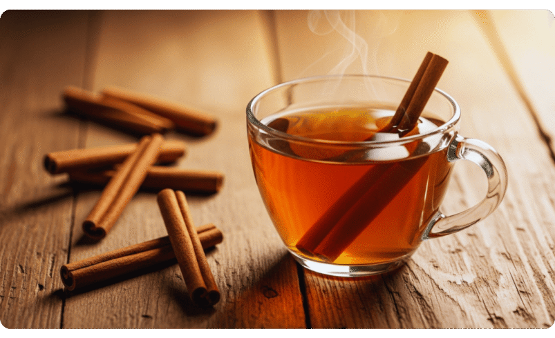Xícara de chá quente com pau de canela sobre uma mesa de madeira.