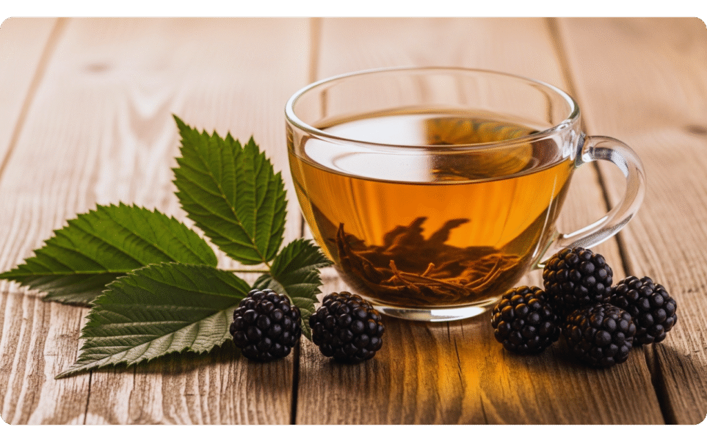 Xícara de chá com folhas de amora e amoras sobre mesa de madeira.