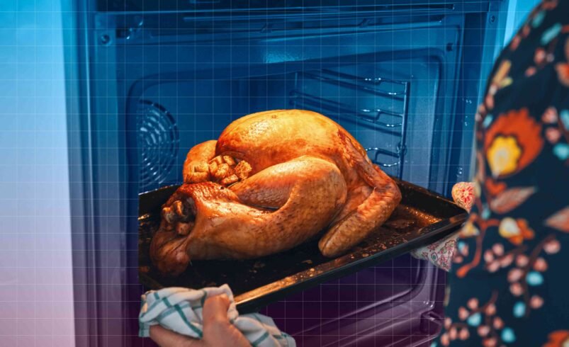 Pessoa retirando frango dourado assado de um forno.