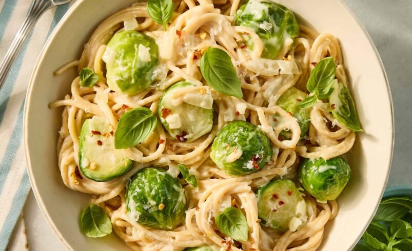 Prato de macarrão com molho cremoso, couve de bruxelas e manjericão.