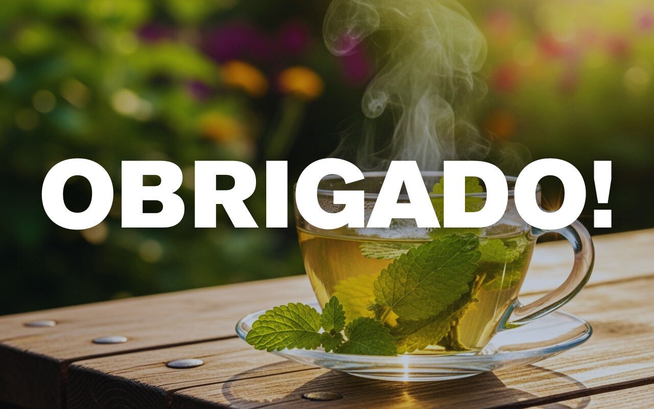 Xícara de chá quente com folhas de hortelã sobre mesa de madeira e fundo desfocado.