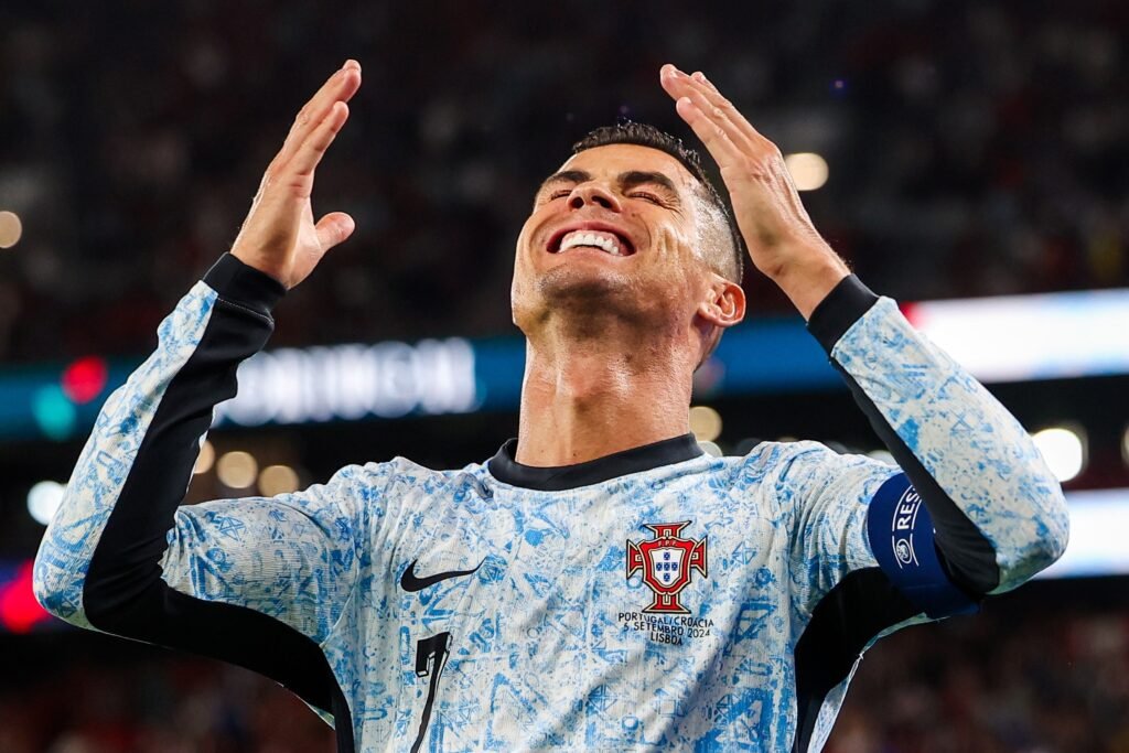 Jogador da seleção de Portugal com uniforme azul celebrando em campo.
