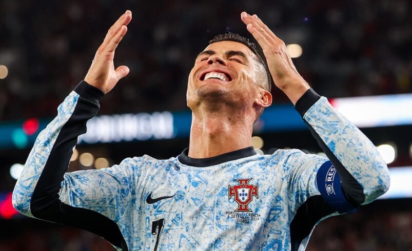 Jogador da seleção de Portugal com uniforme azul celebrando em campo.