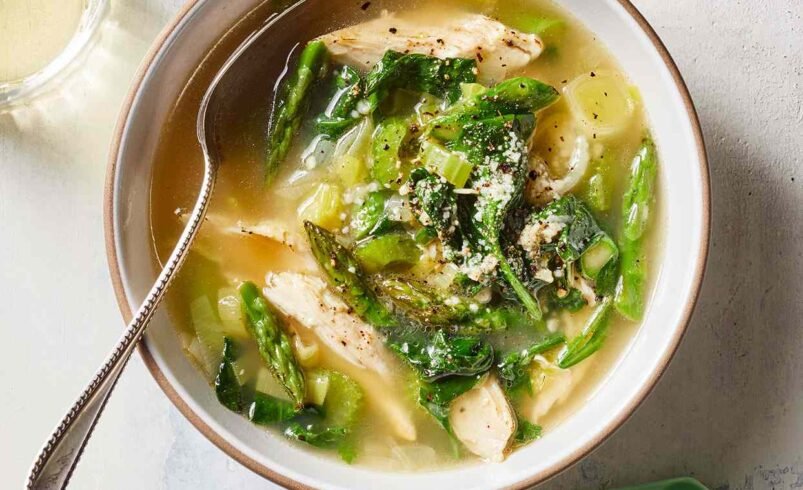 Prato fundo com sopa de frango, espinafre e vegetais frescos.