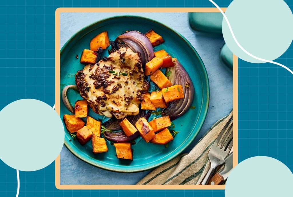 Prato com frango grelhado, cubos de batata-doce assada e fatias de cebola roxa.