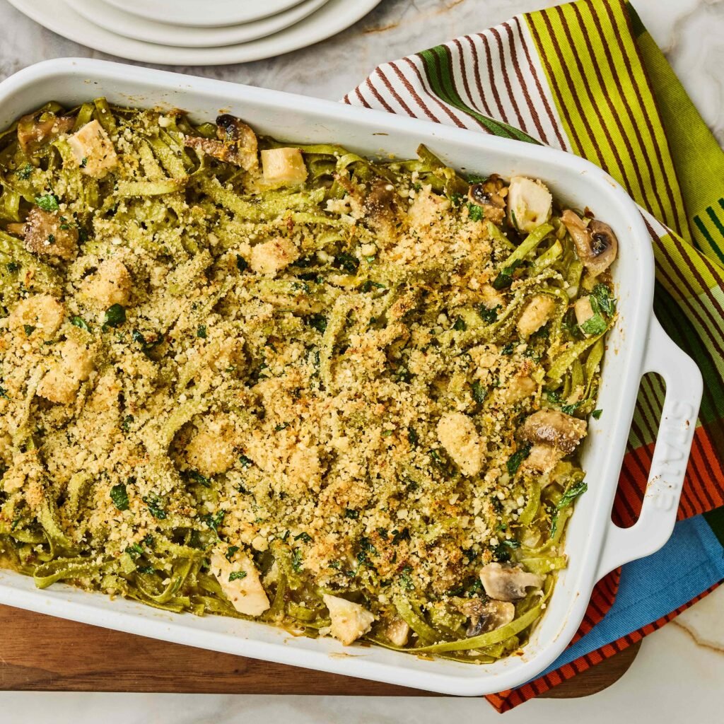 Prato de macarrão cremoso ao forno com cobertura de parmesão e vegetais.