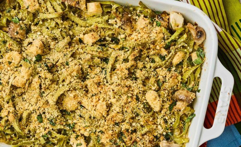 Prato de macarrão cremoso ao forno com cobertura de parmesão e vegetais.