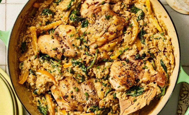 Panela verde com frango grelhado sobre risoto cremoso, espinafre e pimentões.