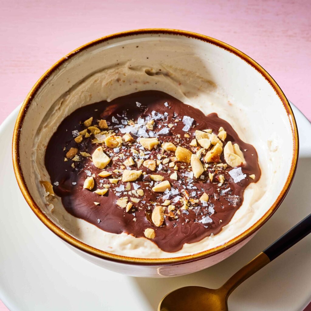 Tigela preenchida com creme de amendoim, cobertura de chocolate, amendoim picado e sal marinho.