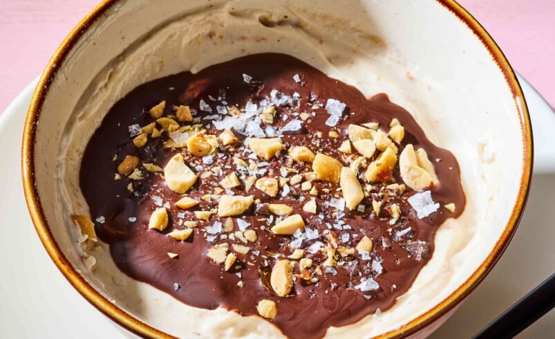 Tigela preenchida com creme de amendoim, cobertura de chocolate, amendoim picado e sal marinho.