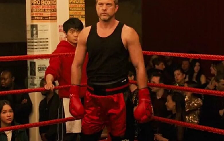 Lutador de boxe no ringue usando luvas vermelhas e roupa vermelha e preta.