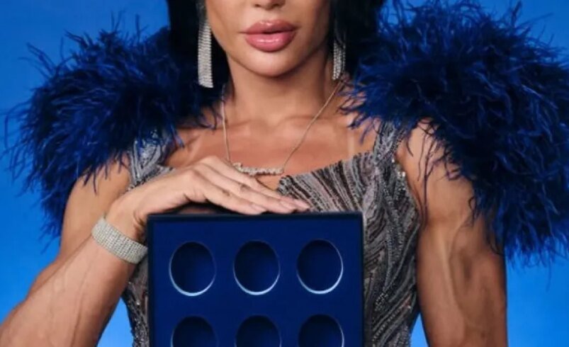 Mulher vestida elegantemente segura um objeto azul com seis círculos vazados.