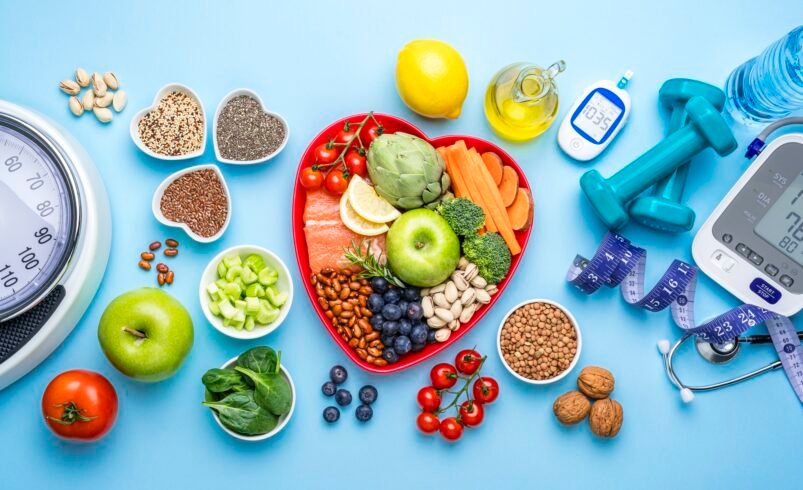 Mesa azul com alimentos saudáveis, equipamentos de saúde e exercícios.