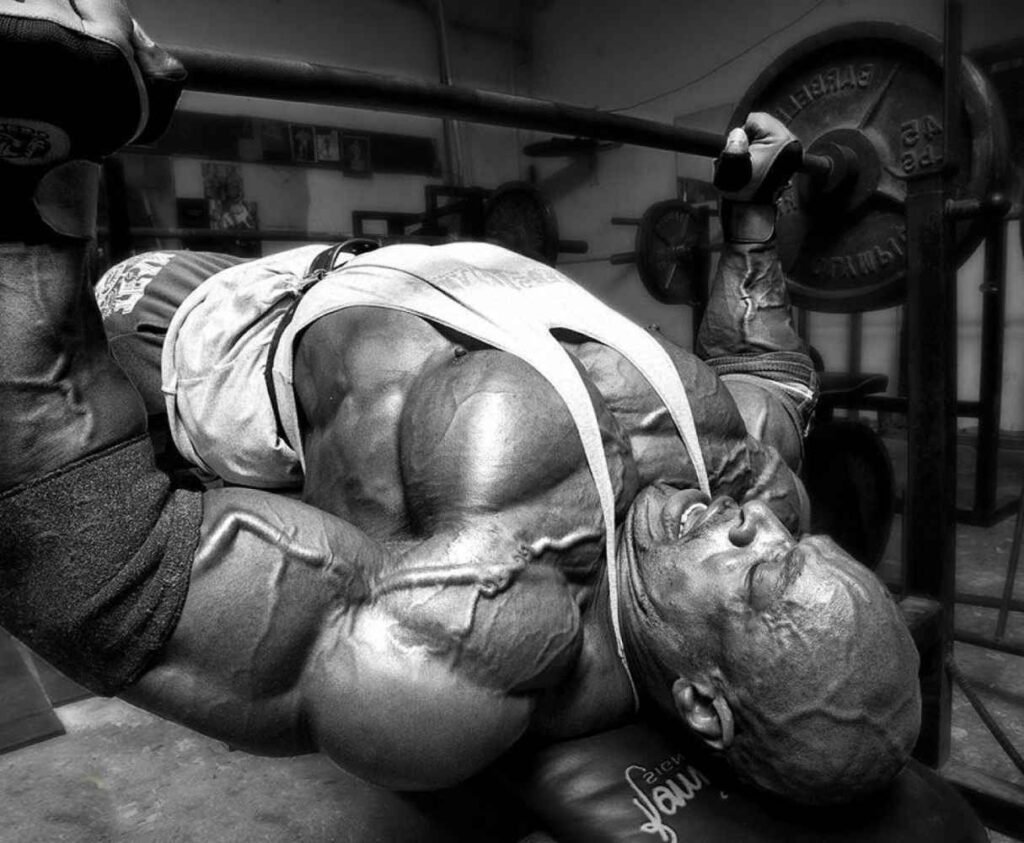 Homem musculoso realizando exercício no supino em academia.