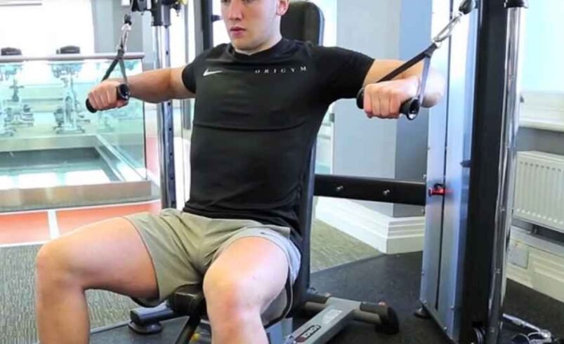 Pessoa usando equipamento de academia para treino de peitoral.