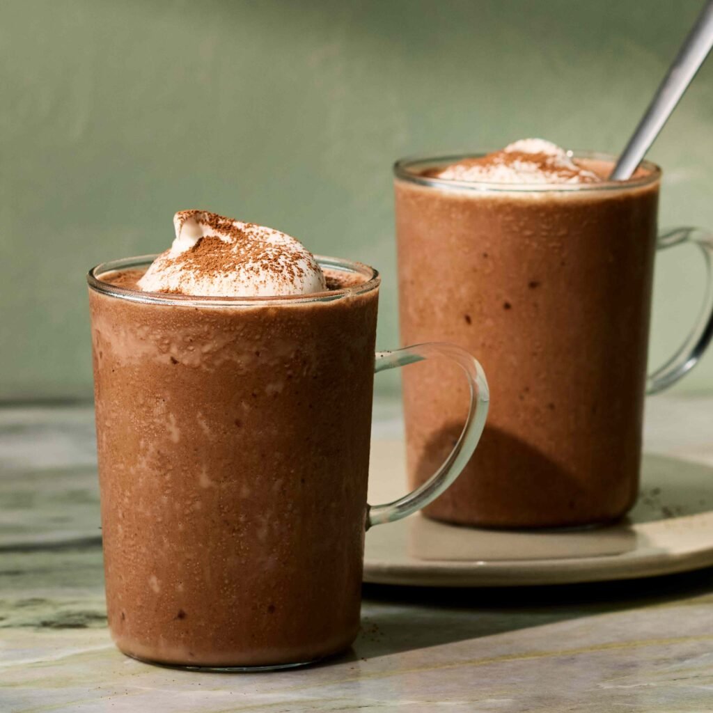 Chocolate Quente Congelado 1 Duas canecas transparentes com smoothie de chocolate coberto com chantilly.