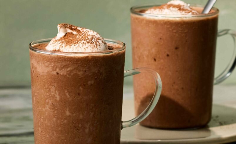 Duas canecas transparentes com smoothie de chocolate coberto com chantilly.