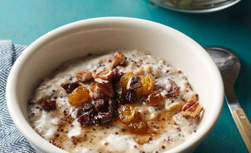 Mingau de aveia em tigela branca com frutas secas e pedaços de nozes.