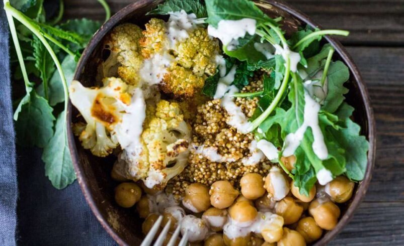 Bowl de grão-de-bico, couve-flor assada, folhas verdes e molho cremoso.