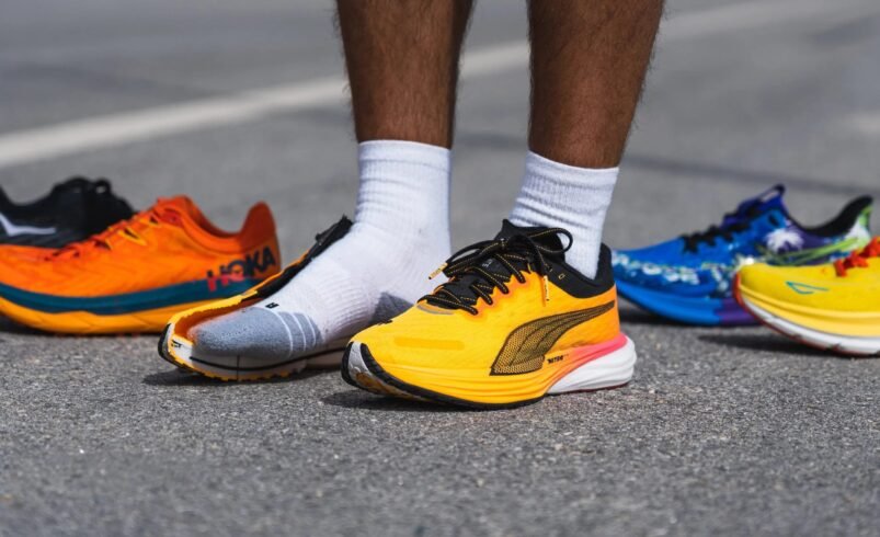 Homem experimentando tênis de corrida coloridos em uma superfície asfaltada.