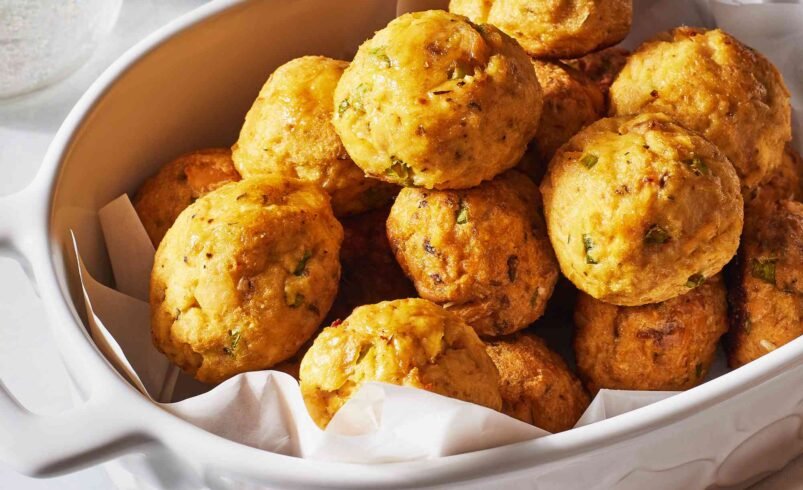 Bolinhos dourados servidos em uma travessa branca sobre guardanapo.