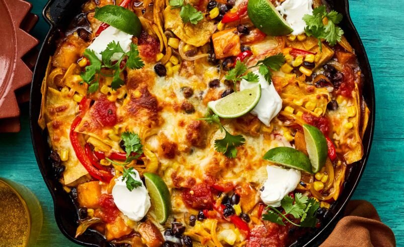 Nachos em panela de ferro com queijo derretido, limão e guarnições.