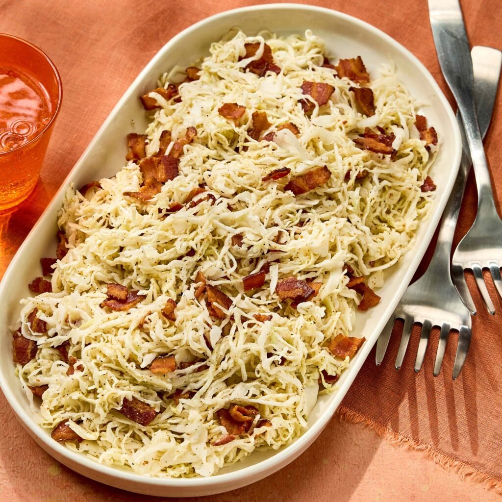 Prato branco oval com salada de repolho ralado e pedaços de bacon.