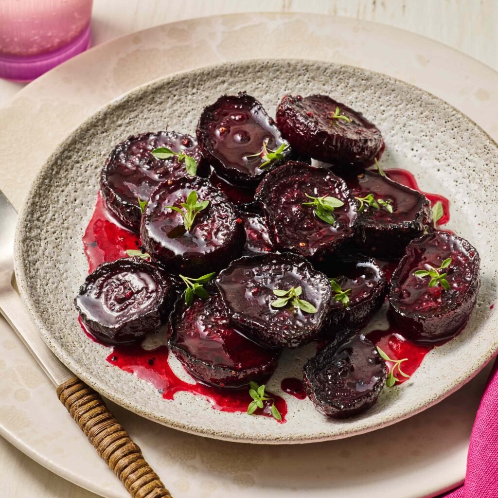 Prato de beterrabas assadas decoradas com ervas frescas em prato de cerâmica.