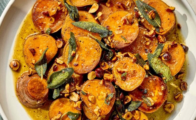 Prato de batata-doce caramelizada com sálvia e nozes em um prato branco.