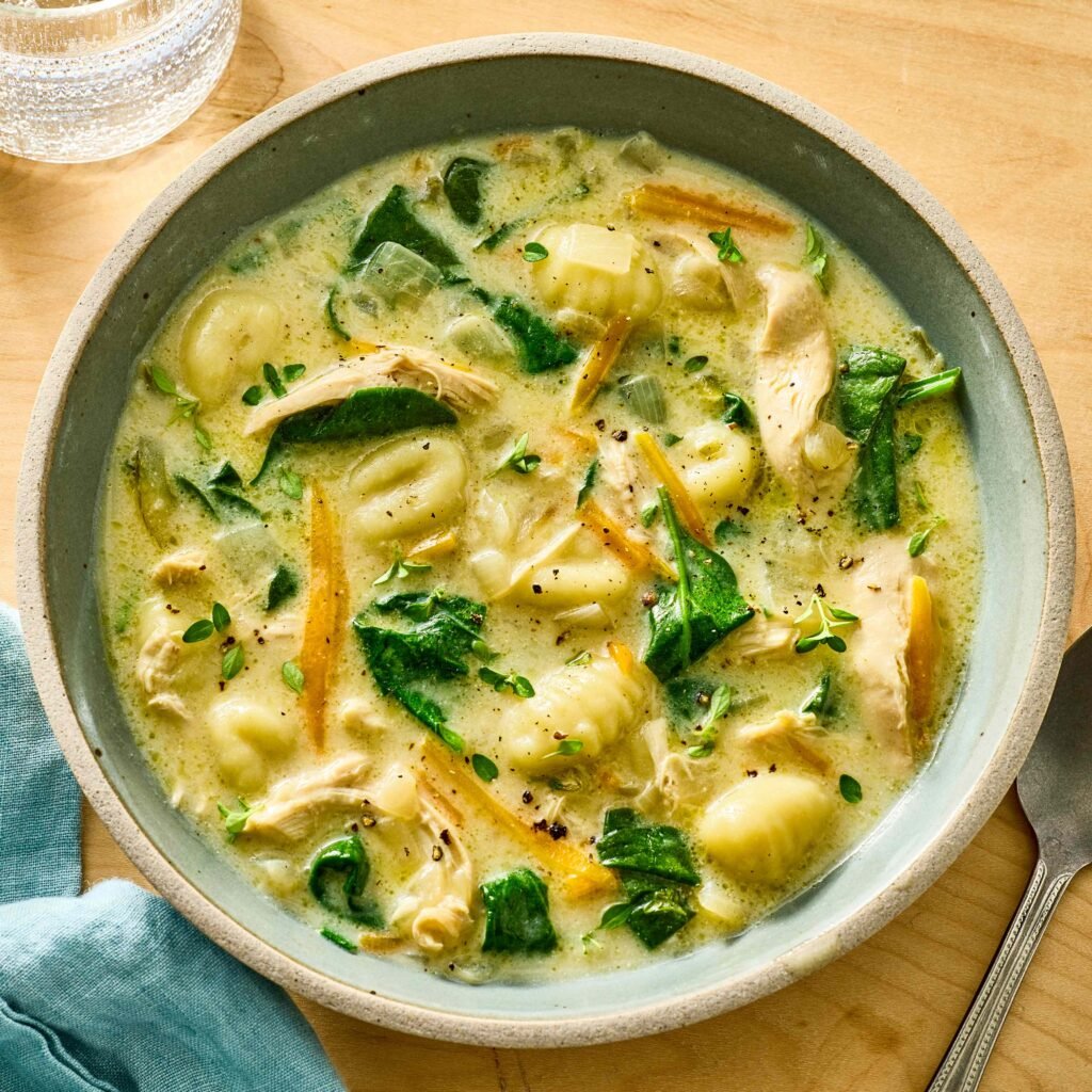 Tigela de sopa cremosa com nhoque, frango e espinafre frescos.