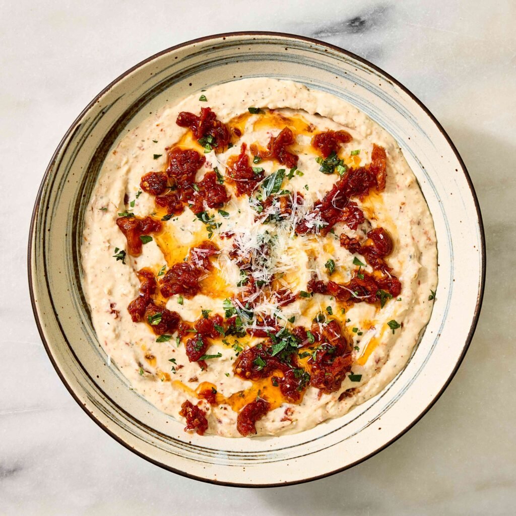 Tigela com creme de feijão branco, molho de tomate e ervas.