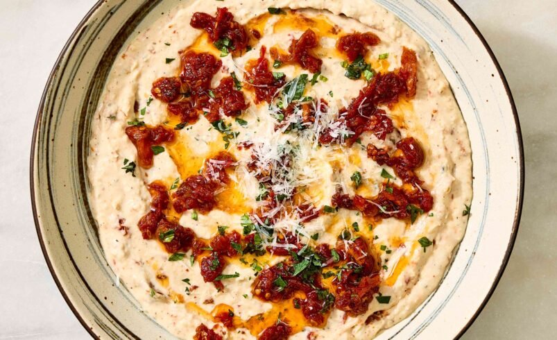 Tigela com creme de feijão branco, molho de tomate e ervas.