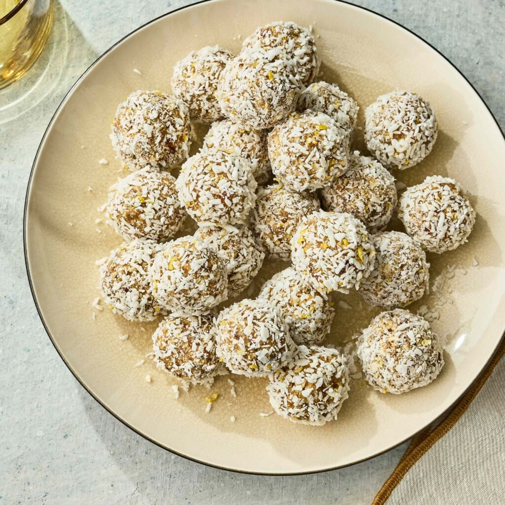 Vários doces cobertos com coco ralado dispostos em prato claro.