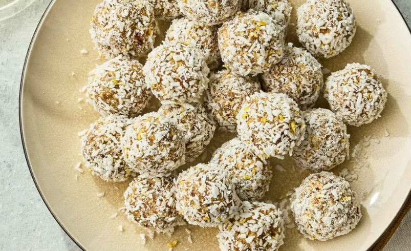 Vários doces cobertos com coco ralado dispostos em prato claro.