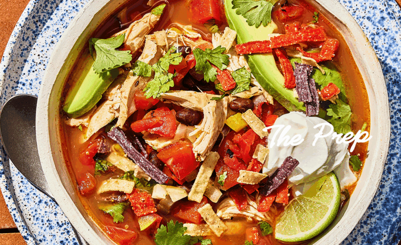 Tigela de sopa de frango mexicana com guarnições coloridas de abacate, coentro e tortilhas crocantes.