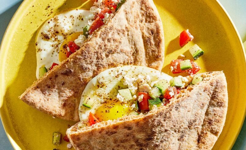 Dois pedaços de pão sírio recheados com ovos, tomate, pepino e queijo feta.