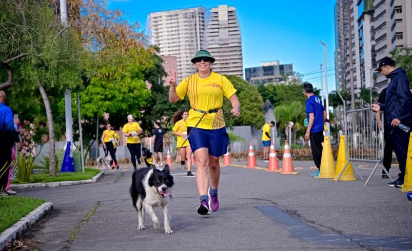 Pessoa correndo com cachorro em área urbana durante evento esportivo.