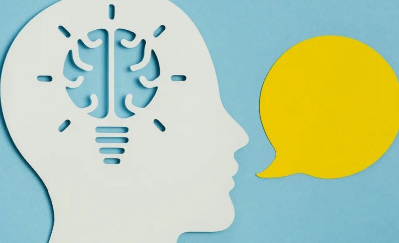 Silhueta de uma cabeça branca com cérebro em formato de lâmpada ao lado de balão amarelo de fala.