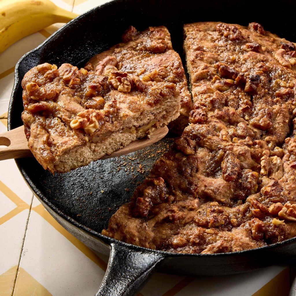 Fatias de bolo de banana com nozes em frigideira de ferro fundido.