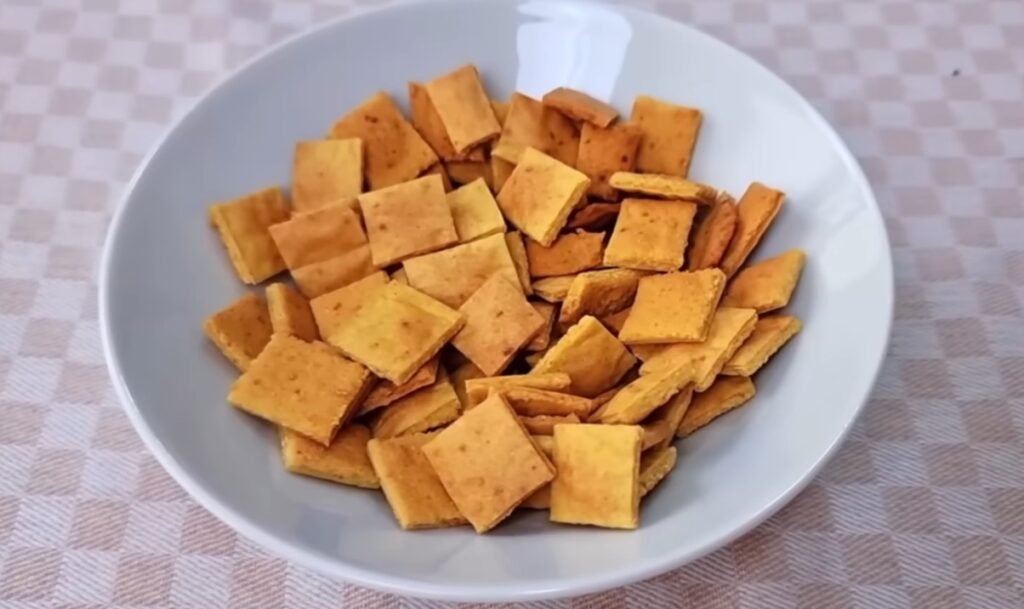 Prato branco com biscoitos quadrados sobre uma toalha xadrez.