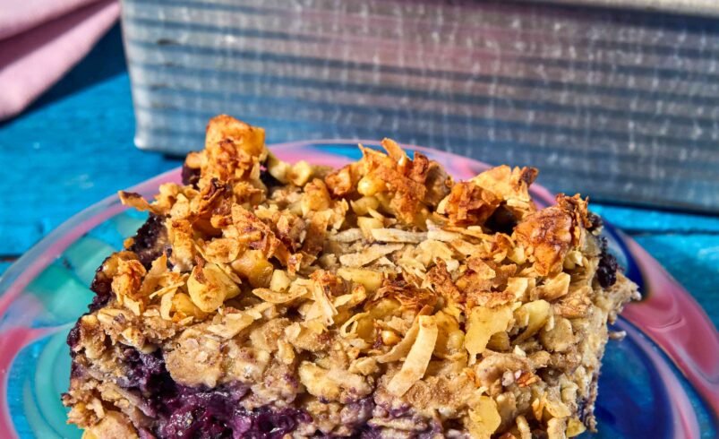 Barrinha de frutas com cobertura dourada sobre prato colorido e forma ao fundo.