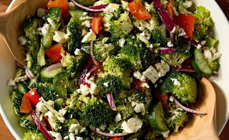 Tigela de salada com brócolis, pepino, tomate, cebola roxa e queijo feta.