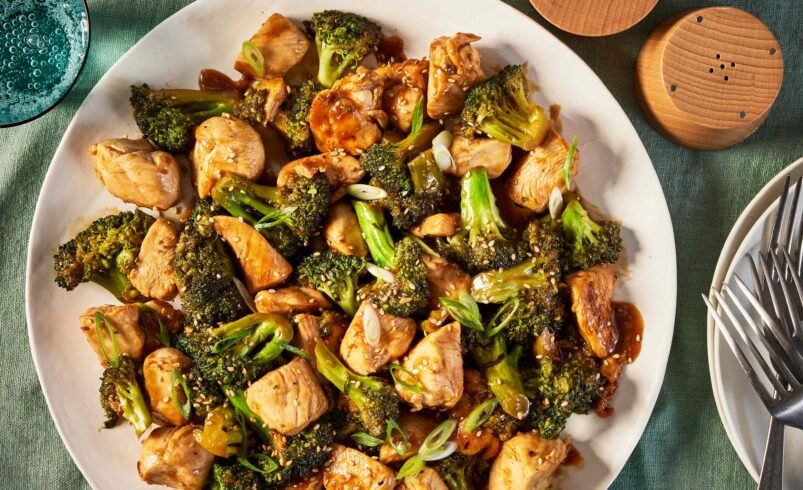 Prato de frango com brócolis grelhados servido em uma mesa verde.