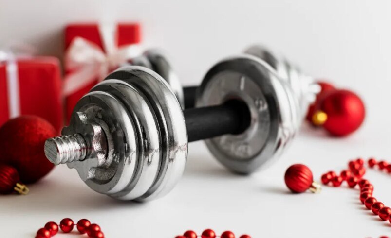 Halter de metal entre enfeites de Natal e presentes em fundo branco.