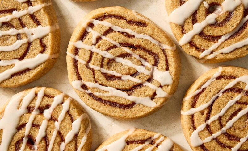 Biscoitos em formato espiral com recheio de canela e cobertura de glacê branco.