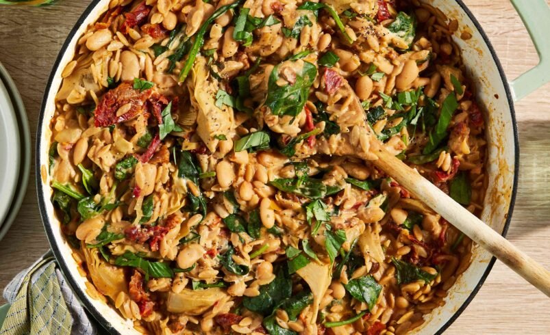 Panela com ensopado de feijão branco, espinafre e tomates secos.