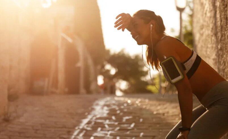 Pessoa em roupa esportiva descansando em rua de pedra ao amanhecer.