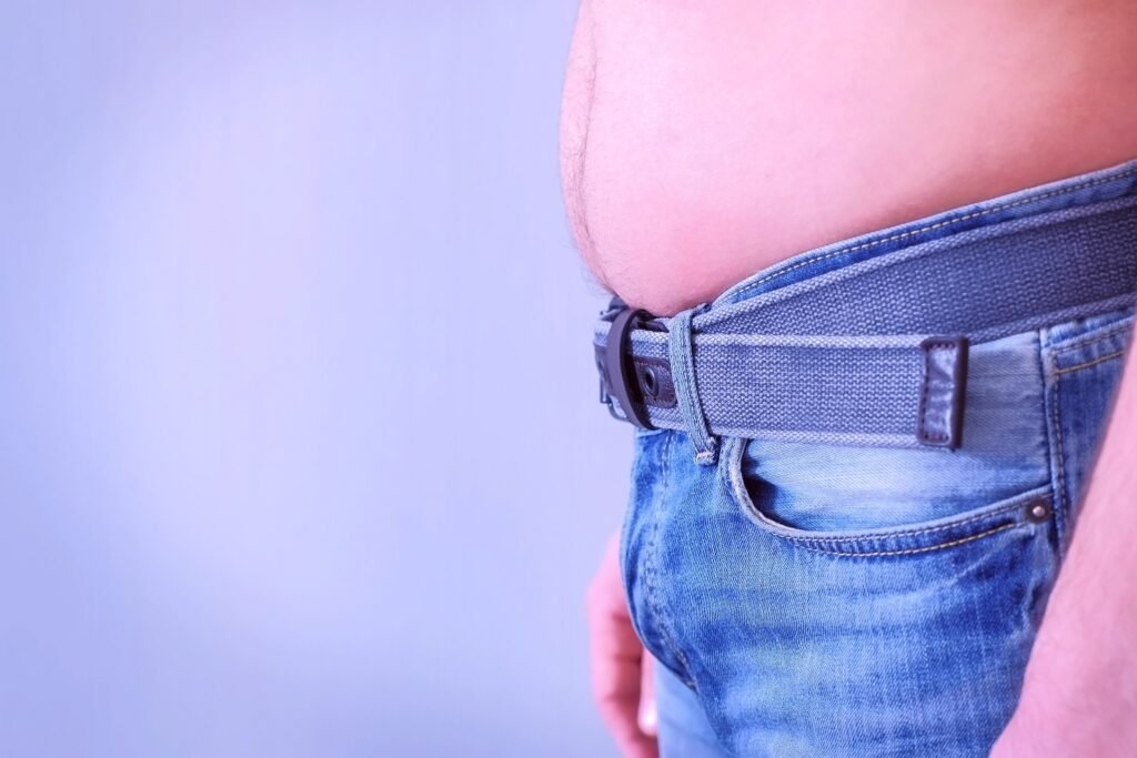 Cintura de um homem vestindo calça jeans com cinto ajustado.