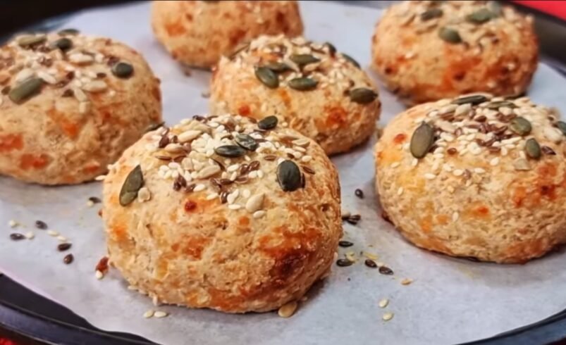 Pães caseiros cobertos com sementes em uma assadeira.