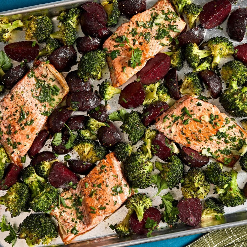 Filés de salmão assados com brócolis e beterraba em uma assadeira.